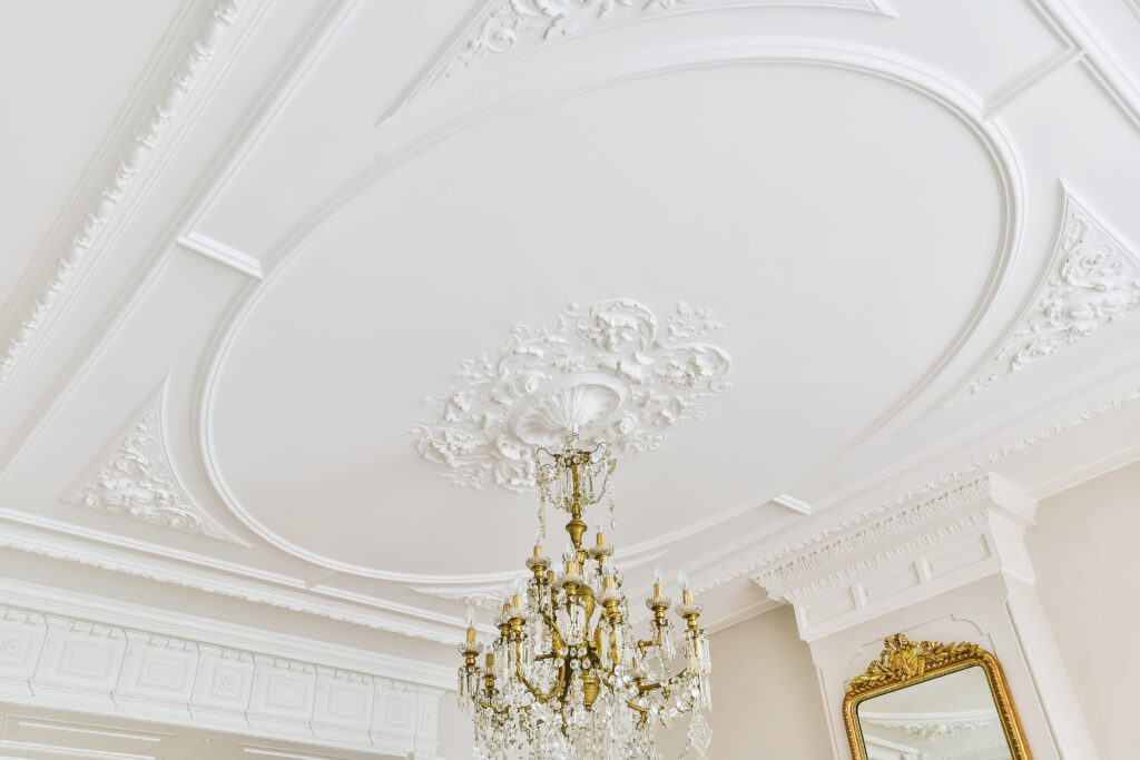 Klassiek ornamentenplafond met een vierkante sierlijst en kristallen kroonluchter.