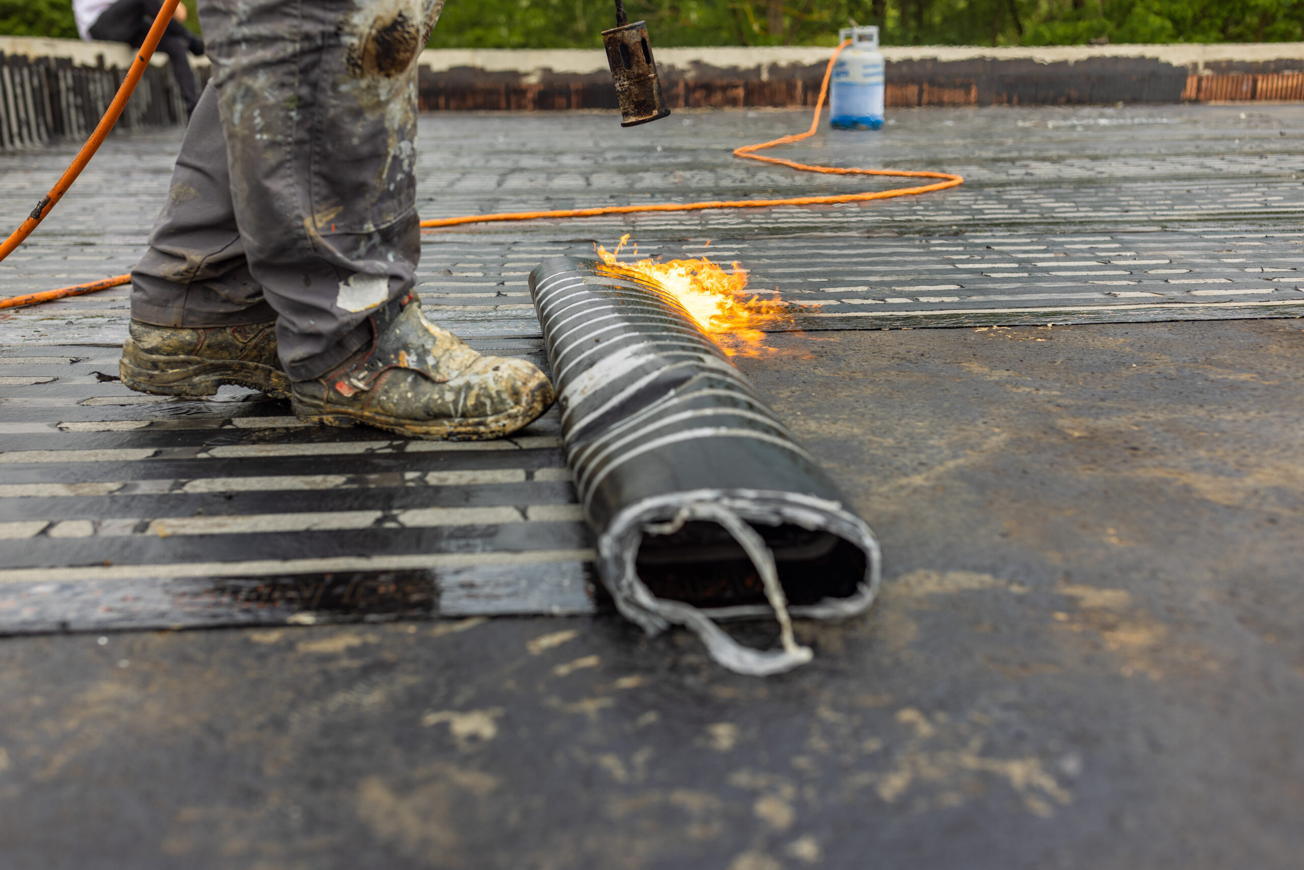 Bitumen dakbedekking wordt aangebracht op een plat dak door een dakdekker met een brander.