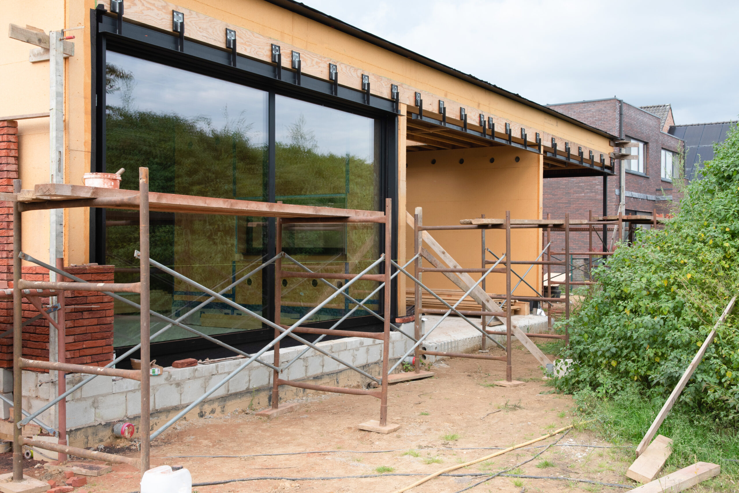 Verbouw en uitbreiding van een huis met steigers en nieuwe gevelconstructie.