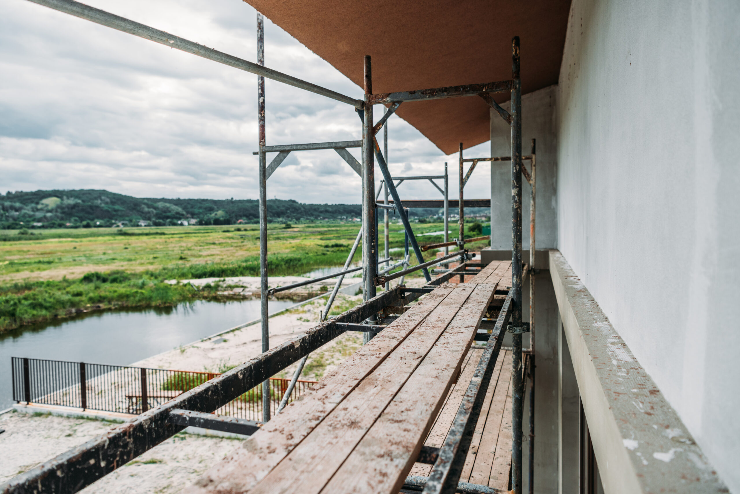 Restauratie van een historisch pand met steigers langs de gevel en een uitzicht op het platteland.